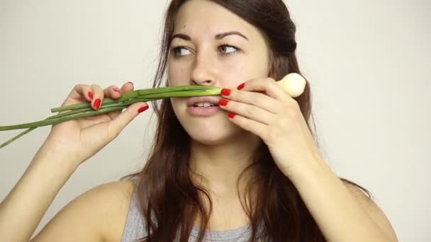 Hermosa mujer joven comiendo verduras. sosteniendo cebollas verdes. comida saludable - concepto corporal saludable — Vídeos de Stock