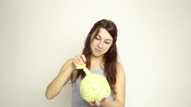 Hermosa mujer joven comiendo verduras. sosteniendo la col, ella mira a la cabeza de la col. comida saludable - concepto corporal saludable — Vídeo de stock