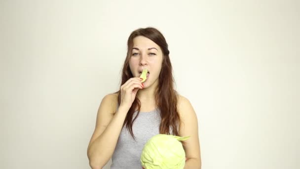 Hermosa mujer joven comiendo verduras. sosteniendo la col, ella mira a la cabeza de la col. comida saludable - concepto corporal saludable — Vídeo de stock