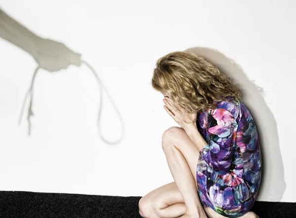 Vyděšená žena stojící u zdi s anonymní člověk, který drží pás, koncepční natáčení zachycující proces a důsledky domácího násilí — Stock fotografie