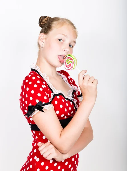 Porträt eines glücklichen schönen jungen Mädchens mit süßen Bonbons. hübsche junge Frau in einem roten Kleid mit weißen Tupfen und zwei bunten Lutschern — Stockfoto