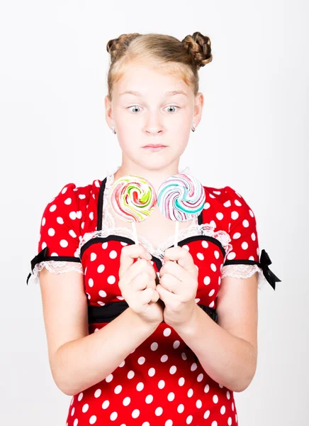 Retrato de menina bonita feliz com doces doces. bonita jovem mulher vestida em um vestido vermelho com bolinhas brancas segurando dois pirulito colorido — Fotografia de Stock