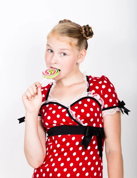 甜蜜的糖果快乐的美丽年轻女孩的画像。年轻漂亮的女人穿着一件红色的衣服与白色波尔卡圆点抱着两个七彩的棒棒糖 — 图库照片