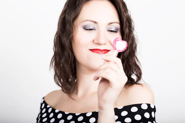 Retrato de feliz hermosa joven lamiendo dulces dulces y expresando diferentes emociones. bonita mujer con corazón en forma de piruleta —  Fotos de Stock