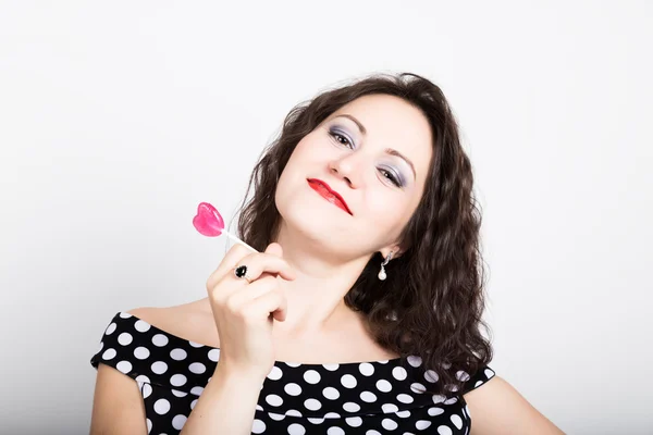 Retrato de feliz hermosa joven lamiendo dulces dulces y expresando diferentes emociones. bonita mujer con corazón en forma de piruleta — Foto de Stock