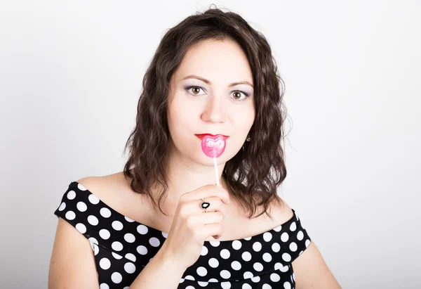 Retrato de feliz hermosa joven lamiendo dulces dulces y expresando diferentes emociones. bonita mujer con corazón en forma de piruleta — Foto de Stock