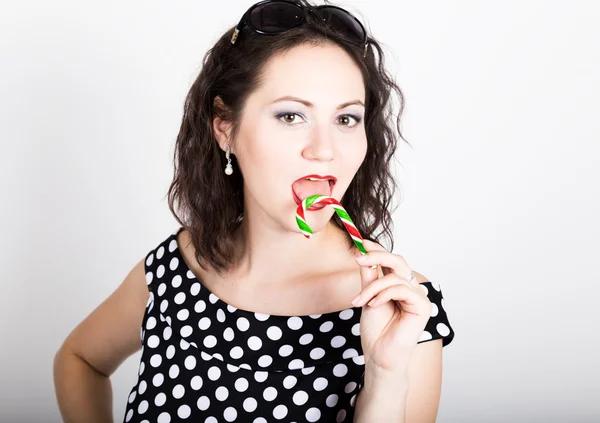 Retrato de feliz hermosa joven lamiendo dulces dulces y expresando diferentes emociones. bonita mujer con corazón en forma de piruleta — Foto de Stock