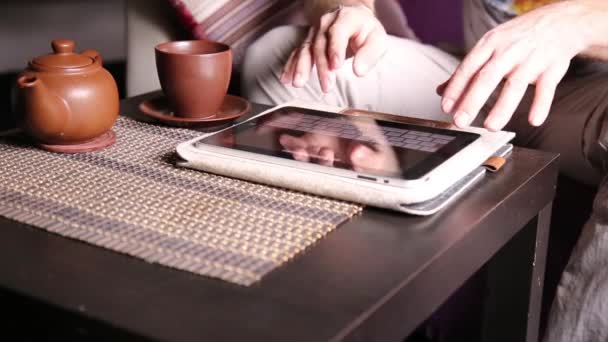 Νέος επιχειρηματίας χρησιμοποιώντας υπολογιστή tablet για online αγορές. Ο άνθρωπος εργάζεται για pc tablet και πίνοντας τσάι στο café — Αρχείο Βίντεο