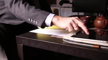 Ofis Masası oturan işadamı bunları, pc tablet ile karşılaştırarak bir tasarıyı imzalar. yakın çekim yakışıklı bir erkek ve bir dolma kalem