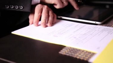 Ofis Masası oturan işadamı bunları, pc tablet ile karşılaştırarak bir tasarıyı imzalar. yakın çekim yakışıklı bir erkek ve bir dolma kalem
