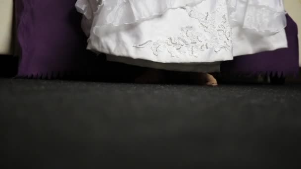 Jonge bruid aankomt op de Bank, uitkleden trouwjurk. Close-up van benen — Stockvideo