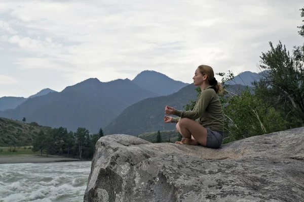 Młoda kobieta siedzi na skraju klifu nad rzeka góry — Zdjęcie stockowe