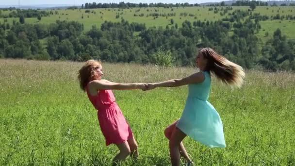 dvě mladé přítelkyně krouží ruku v ruce na zelené louce