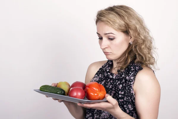 美しい若い女性が、野菜を食べること。野菜、赤唐辛子、トマト、キュウリとプレートを保持しています。健康食品 - 強力な歯とボディケアのコンセプト — ストック写真