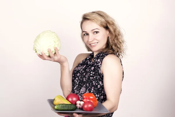 Bela jovem mulher comendo um legumes. segurando um prato com verduras, pimentão vermelho, tomate, pepino. alimentos saudáveis - dentes fortes e conceito de cuidados com o corpo — Fotografia de Stock