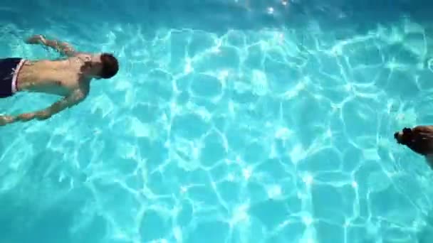 La coppia si riposa in piscina con lo champagne. sorridono, si abbracciano e si baciano . — Video Stock