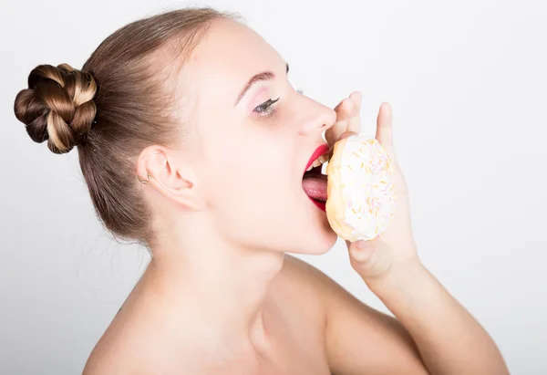 Молодая женщина в ярком макияже ест вкусный пончик с глазурью. Смешная радостная женщина со сладостями, десертом. Концепция диеты. фастфуд. Девушка облизывает пальцы — стоковое фото