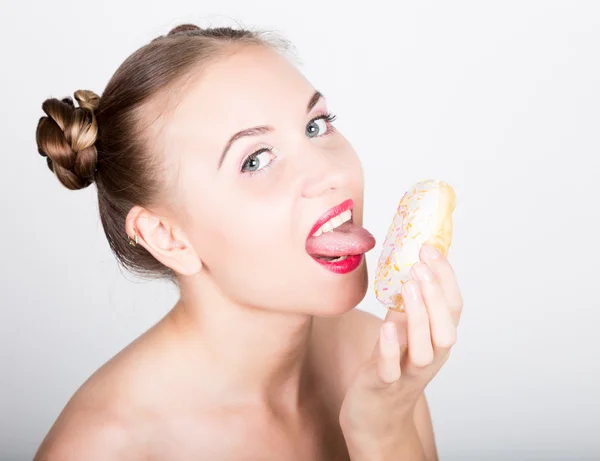 Mujer joven en maquillaje brillante comiendo una rosquilla sabrosa con glaseado. Mujer divertida y alegre con dulces, postre. concepto de dieta. comida chatarra. chica lamiendo sus dedos — Foto de Stock
