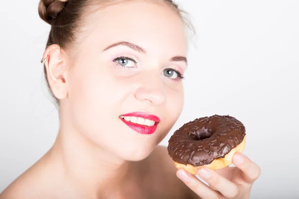 Mujer joven en maquillaje brillante comiendo una rosquilla sabrosa con glaseado. Mujer divertida y alegre con dulces, postre. concepto de dieta. comida chatarra. chica lamiendo sus dedos — Foto de Stock