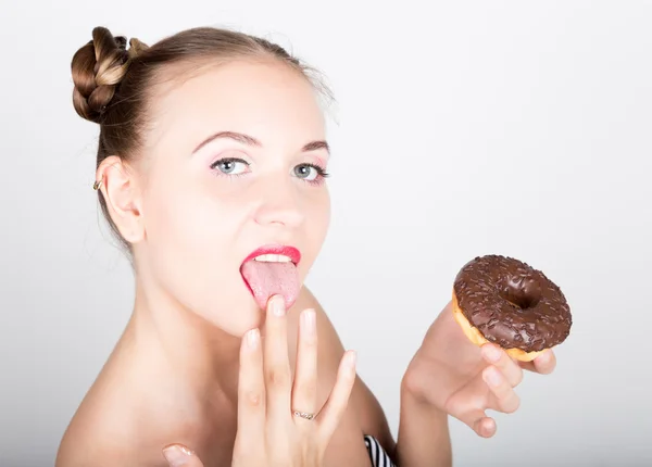 Ung kvinna i ljusa makeup äta en välsmakande donut med glasyr. Funny glad kvinna med godis, dessert. bantning koncept. skräpmat. tjej slickar sina fingrar — Stockfoto