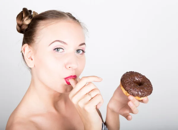 Mujer joven en maquillaje brillante comiendo una rosquilla sabrosa con glaseado. Mujer divertida y alegre con dulces, postre. concepto de dieta. comida chatarra. chica lamiendo sus dedos — Foto de Stock