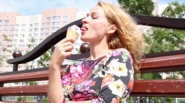 Bir şehir parkta bir bankta oturmuş ve dondurma yemek oldukça mutlu kadın