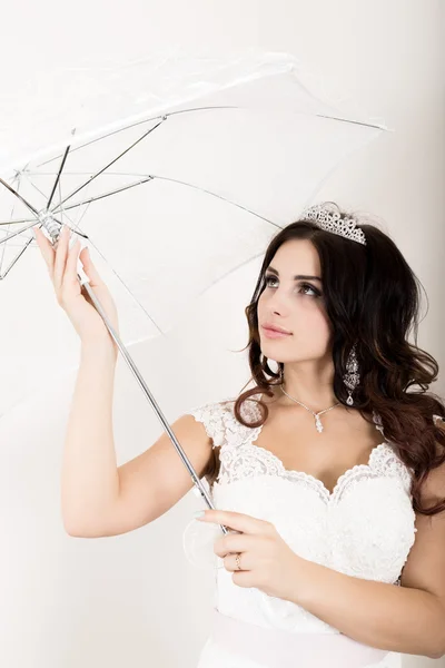 Zbliżenie Portret młodej pięknej panny młodej w sukni ślubnej z makijażu ślubnej i fryzurę. Dziewczyna trzyma biały parasol — Zdjęcie stockowe