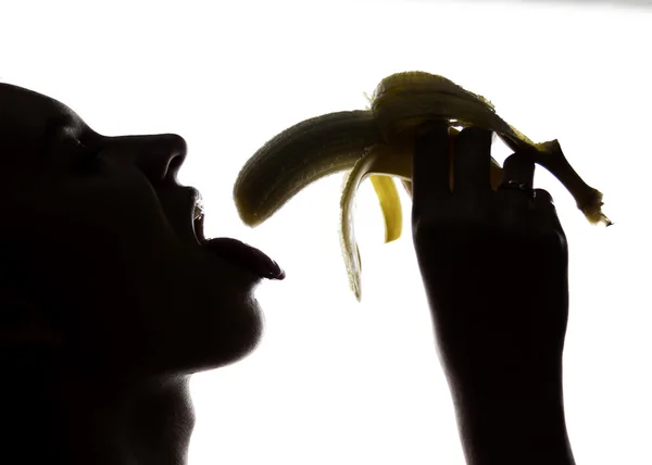 Primo piano di Giovane donna stupita che tiene una banana, sta per mangiare una banana. succhia una banana — Foto Stock