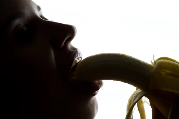 Primo piano di Giovane donna stupita in possesso di banana, sta per mangiare una banana. succhia una banana — Foto Stock