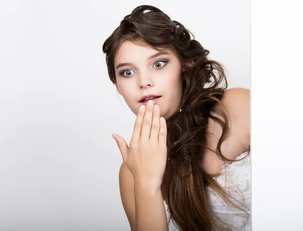 Sorrindo feliz jovem mulher de pé atrás e inclinando-se em um cartaz branco em branco ou cartaz, expressa diferente — Fotografia de Stock