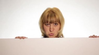 Gülümseyen mutlu kadın arkasında duran ve beyaz boş bir reklam panosu veya pankart yaslanmış, farklı duyguları ifade eder ve bir pankart arkasında saklanıyor. beyaz arka plan üzerinde