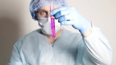 şişesi tutarak ve deney ilerlemesini izlerken bilim adamı doktor tıbbi üniformalı