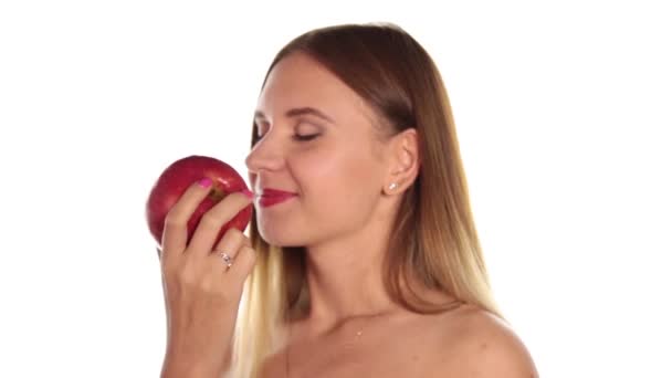 Naga młoda kobieta nosi czerwoną szminkę i ma włosy w dół i szczotkowane, duże, ciemne, Czerwone jabłko jedzenie. Zdrowa żywność - koncepcja silne zęby. Na białym tle — Wideo stockowe