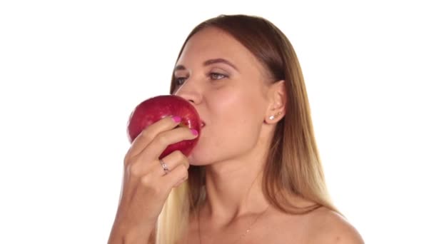 Jeune femme nue porte rouge à lèvres et a les cheveux vers le bas, et brossé, manger une grosse pomme rouge foncé. aliments sains - concept de dents fortes. Sur fond blanc — Video