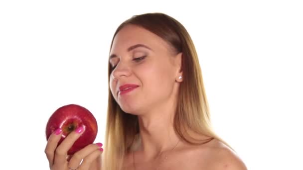 Mujer joven desnuda usa lápiz labial rojo y tiene el pelo suelto, y cepillado, comiendo una manzana grande, de color rojo oscuro. comida saludable - concepto de dientes fuertes. Sobre un fondo blanco — Vídeos de Stock