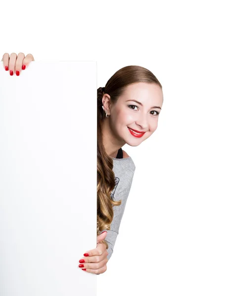 Sonriente joven feliz de pie detrás y apoyado en una cartelera blanca en blanco o cartel, expresa diferentes — Foto de Stock
