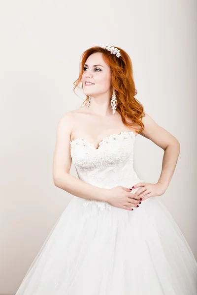 red-haired bride in a wedding dress, bright unusual appearance. Beautiful wedding hairstyle and bright make-up