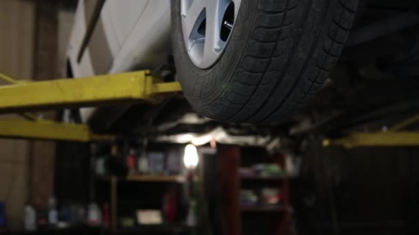 Heffen van een auto op lift in workshop van service station — Stockvideo