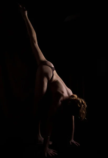 Vista posterior del hermoso fondo femenino, cuerpo desnudo sobre un fondo negro. mujer delgada haciendo asanas de yoga — Foto de Stock