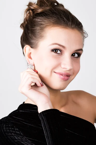 Porträt der jungen Frau in einem schwarzen Kleid, das Ohrringe korrigiert — Stockfoto