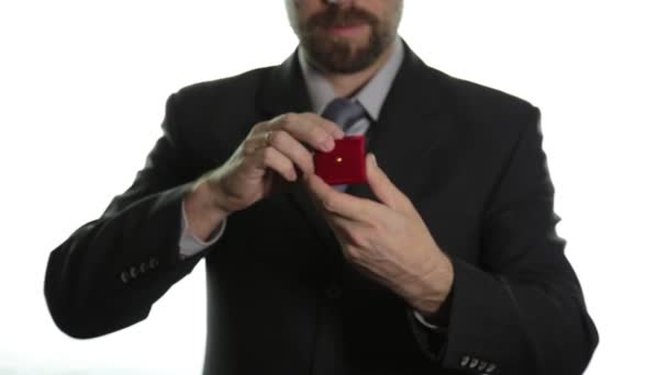 Γενειοφόρος άνδρας σε ένα επαγγελματικό κοστούμι δίνει ένα δαχτυλίδι στο κόκκινο πλαίσιο και εκφράζει διαφορετικά συναισθήματα — Αρχείο Βίντεο