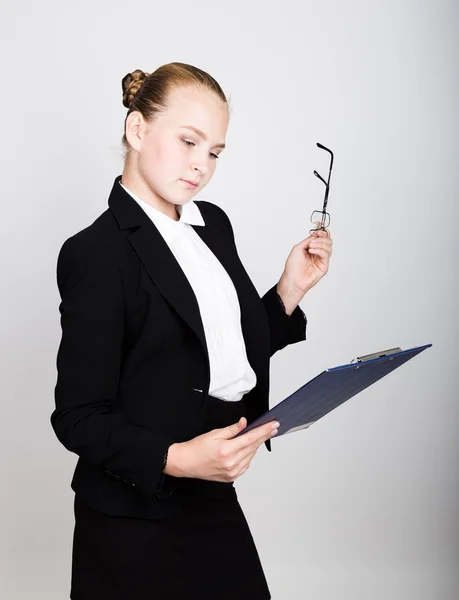 Una donna d'affari con gli occhiali ha pensato a una nuova idea. Studio ritratto di bambina in stile business in possesso di documenti . — Foto Stock