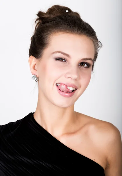 Nahaufnahme Modefoto der jungen Dame in elegantem schwarzen Kleid, verspielte Frau zeigt Zunge — Stockfoto