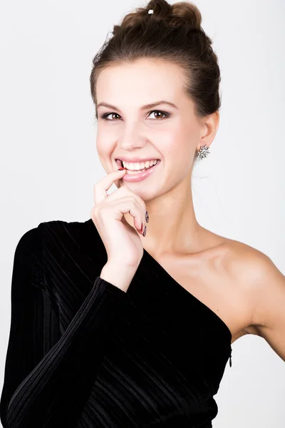 Nahaufnahme Modefoto der jungen Dame in elegantem schwarzen Kleid, verspielte Frau hob Zeigefinger zu seinen Lippen Stockfoto
