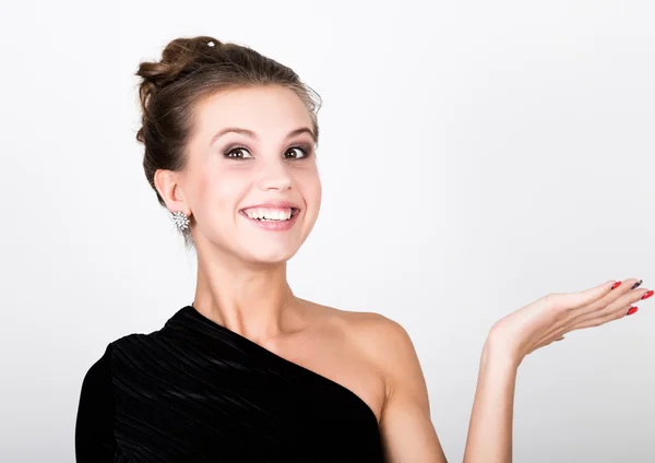 Foto de cerca de la moda joven dama en vestido negro elegante, mujer juguetona sonriendo y muestra su mano — Foto de Stock