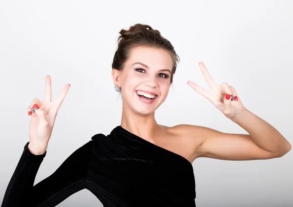 Close-up de moda foto jovem senhora em vestido preto elegante, mulher brincalhão sorrindo e mostra um sinal de paz — Fotografia de Stock