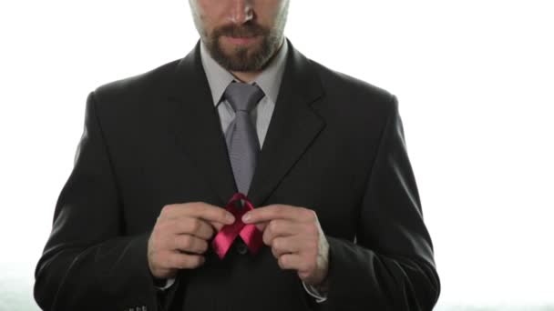 Gros plan des mains de l'homme tenant un ruban rouge foncé de sensibilisation aux incapacités. concept de santé et de médecine — Video