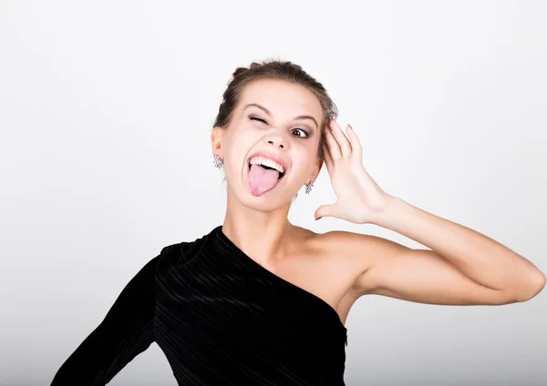 Närbild mode foto av ung dam i elegant svart klänning, lekfull kvinna visar tungan — Stockfoto