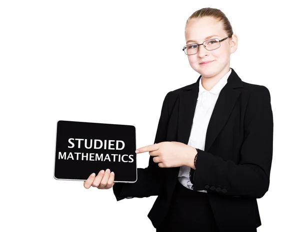 Mooie schoolmeisje in een Business Suit houdt een PC Tablet in zijn handen en op zoek naar de camera, op een PC Tablet inscriptie studeerde wiskunde — Stockfoto