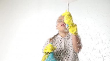 gülümseyen küçük ev hanımı bir sprey, bez ve deterjan ile pencereyi yıkadı. Köpük büyük cam. Ev işi konsepti.